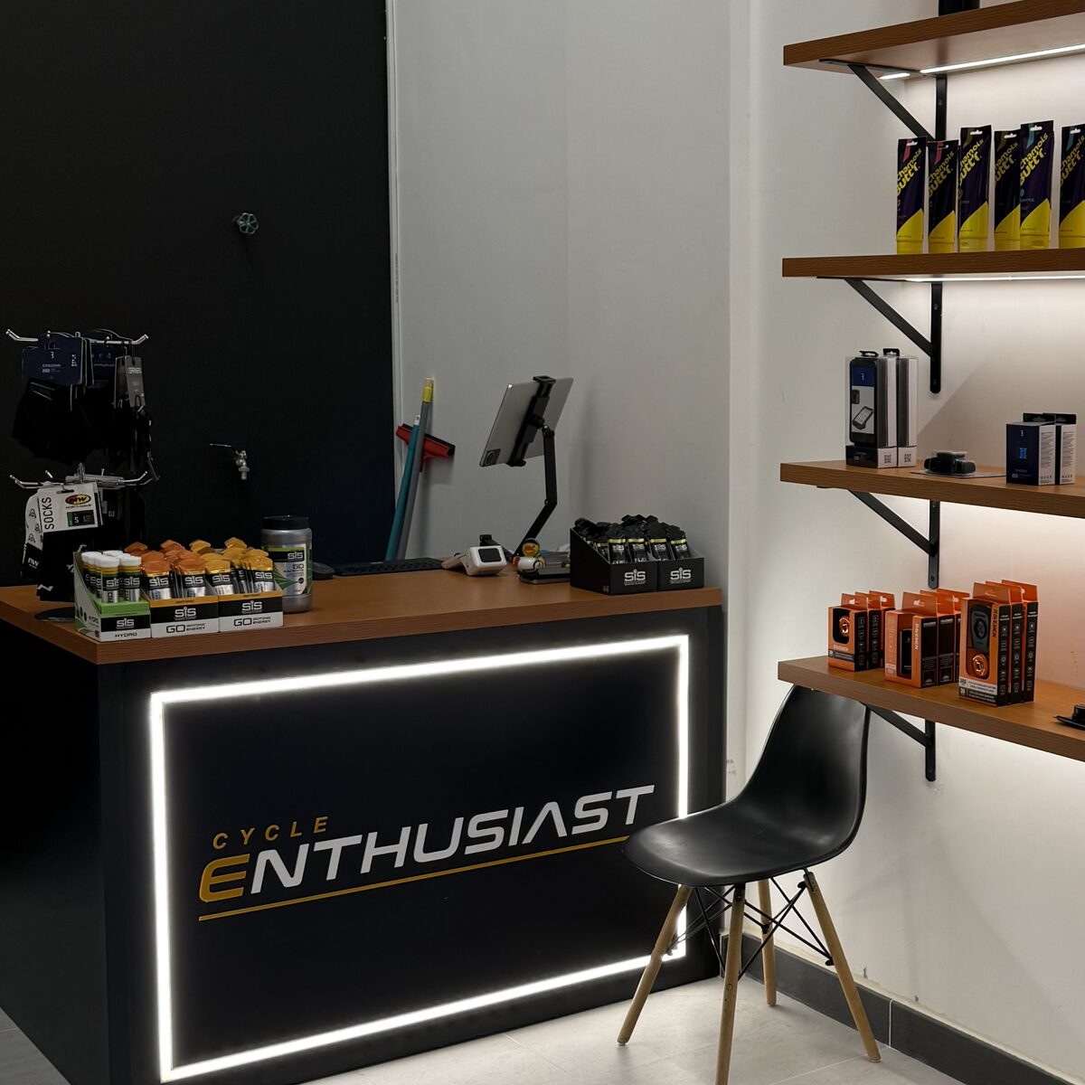 Cycle Enthusiast store counter with illuminated logo and accessory shelves
